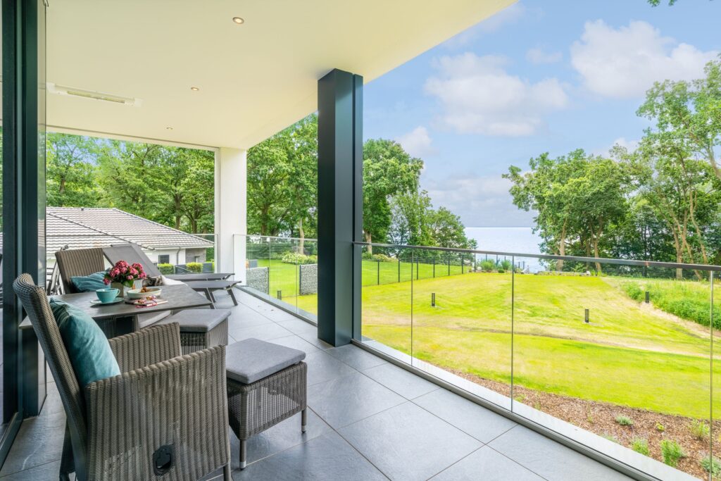 Terrasse des Apartments „Smilla“ in den Luxus-Ferienwohnungen DECK9 am Haff mit Sitzbereich und Blick ins Grüne auf Usedom.