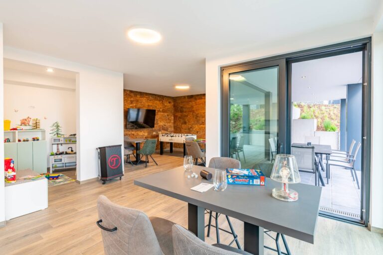 Moderner Gemeinschaftsraum mit Spielbereich, Tisch und Terrasse in den Ferienwohnungen DECK9 auf Usedom