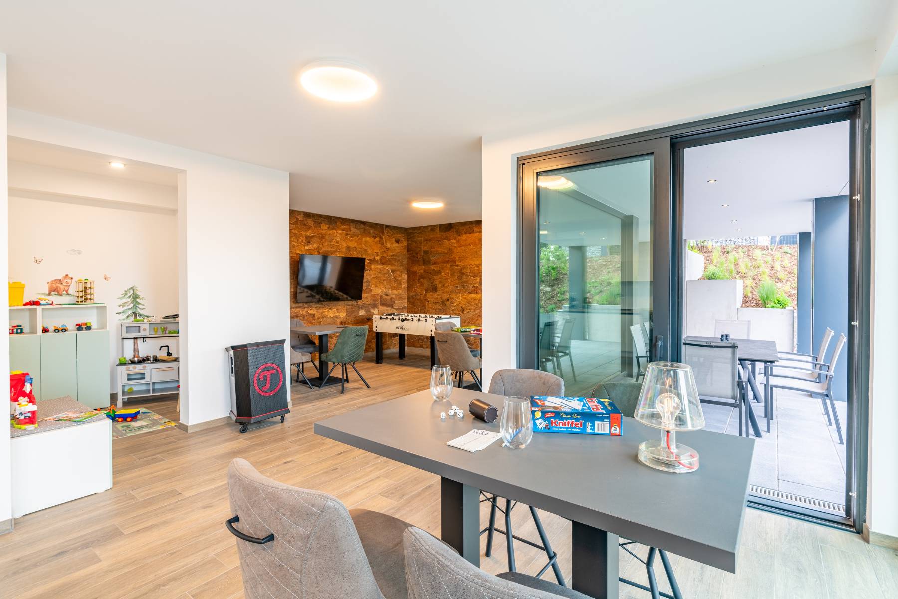 Moderner Gemeinschaftsraum mit Spielbereich, Tisch und Terrasse in den Ferienwohnungen DECK9 auf Usedom